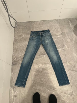Tiger of sweden  straight jeans blå - Säljer ett par klassiska Levi's 501 jeans i blå tvätt med snygga slitningar och raka ben. Jeansen har fem fickor, knappgylf och bruna sömmar. Passar dig som gillar tidlös stil och vill ha ett par jeans med autentisk känsla. 29.32 