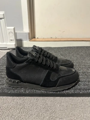 Valentino rockrunners svarta - Svarta Valentino Garavani Rockrunner sneakers med snygga detaljer, skick 8/10 kan bli 9/10 med en snabb tvätt, det ända slitna är på innersulan under hälen och under skon. Storlek 42. Inget og därav priset, vill bara bli av mer skorna. Skorna har en mix av mocka och textil, samt coola nitar på hälen. Klassisk snörning och rund tå. Perfekta för dig som gillar stilrena och exklusiva sneakers. Kan gå ner till 1499 vid snabb affär. 