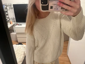 Vit stickad tröja - Mysig vit stickad tröja med rund hals och ribbade muddar. Tröjan har ett snyggt mönster med diskreta hål längs axlarna och är långärmad. Fint skick, storlek xs/s🤍