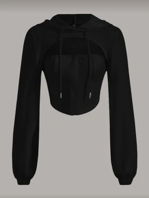 Svart croppad hoodie med dragkedja - Svart croppad hoodie från TZZ med långa ärmar, huva och snörning. Tröjan har en dragkedja framtill och ribbade muddar vid ärmslut. Perfekt för dig som gillar en sportig och trendig look.