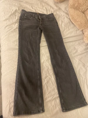 Svarta bootcut jeans från Lee - Snygga svarta jeans från Lee med klassisk femficksdesign och bootcut-ben. Jeansen har normal passform och är tillverkade i ett mjukt bomullsmaterial med dragkedjegylf. Perfekta för dig som gillar en tidlös look med lite utsvängda ben.
