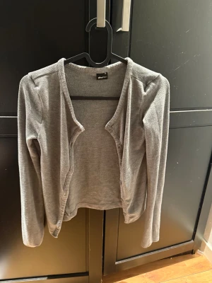 Grå kofta från Gina Tricot - Grå, mjuk och enkel kofta från Gina Tricot med lång ärm och knappar framtill. Säljes då den inte används så mycket, stl xs