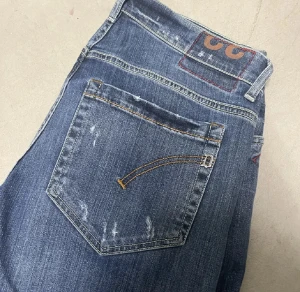 Blå Dondup jeans - Snygga blå jeans från Dondup med klassisk femficksdesign och raka ben. Jeansen har slitna detaljer och kontrastsömmar på bakfickan samt Replay-logga på linningen. Perfekt för dig som gillar en avslappnad och cool stil.