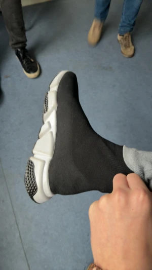 Svarta sock-sneakers med vit sula - Säljer ett par svarta sock-sneakers med chunky vit sula och svarta detaljer undertill. Skorna har en tight stickad ovandel som sitter som en strumpa runt foten och en platt sula med coolt mönster. Perfekta för dig som gillar streetstyle och vill ha något bekvämt och trendigt.