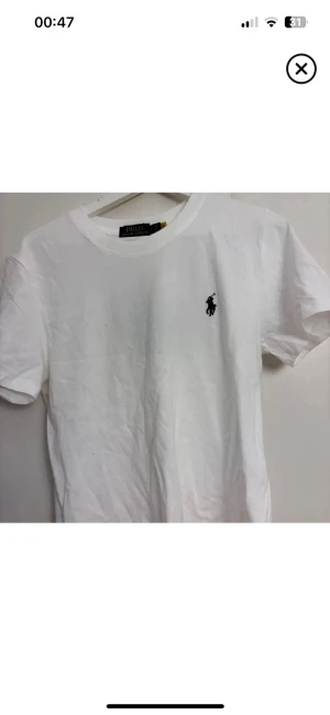 Vit t-shirt från Polo Ralph Lauren - Vit t-shirt storlek M från Polo Ralph Lauren med klassiska svarta Polo-loggan broderad på bröstet och är gjord i mjuk bomull. Enkel och stilren design som funkar till allt. Aldrig använd!!!! Skriv vid funderingar!!!!!