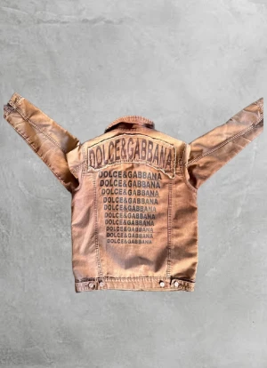 Tvärfet Dolce & Gabbana jacka🔥 - Snygg unik beige jeansjacka från Dolce & Gabbana med tryckt logga i flera rader på ryggen och patchade logodetaljer fram. Klassisk krage, två bröstfickor och knäppning med silvriga knappar. Jackan har en cool, streetig vibe och är tillverkad i bomull. Oerhört niche och rare!