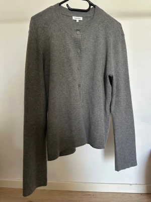 Kofta från Josefin Lavold x Bubbleroom - Grå kofta från Josefin Lavold x Bubbleroom i storlek L. Koftan har långa ärmar, rund halsringning och knappar framtill. Medföljer matchande scarf i samma stickade material.   Obs: Alla plagg säljs endast fram till 28/12 