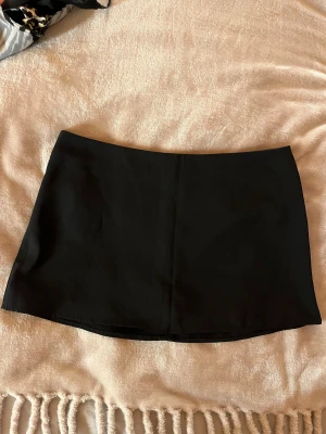 Svart enkel minikjol - Säljer en svart, stilren minikjol med rak passform. Kjolen är kort och har en klassisk look utan detaljer eller mönster. Perfekt att matcha med en oversized tröja🩷