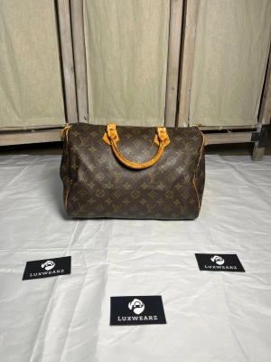 Louis Vuitton Speedy 30 - Louis Vuitton Speedy 30 - Fin tilstand både innvendig og utvendig. Glidelås fungerer som den skal og har ingen defekter. Tab på ene siden har revnet og festene på innsiden av vesken er løs på den ene siden. De er ikke defekte og kan fortsatt brukes uten problem.  - Datecode: VI0911 - Pris: 4499kr - Vesken har autentisk bevis i samarbeid med LegitApp
