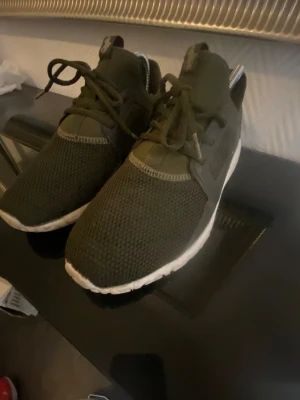 Olivgröna sneakers från Polo Ralph Lauren - Snygga olivgröna sneakers från Polo Ralph Lauren med vit sula och mesh-ovandel. Skorna har snörning och Polo-logga på hälen samt den klassiska hästloggan på plösen. Perfekta för en sportig och stilren look.