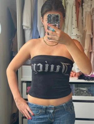 Svart tubtopp Juicy Couture med strass - Svart tubtopp från Juicy Couture i mjuk sammet med glittrande strassdetaljer som bildar texten 'Juicy' framtill. Bandeau-modell som sitter tight och är axelbandslös. Använt bara en gång. Säljer pga för liten.