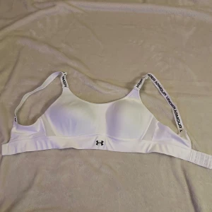 Sport BH - Under Armour  - Säljer en vit sport-BH från Under Armour i storlek M. Aldrig använd, helt ny och sitter jättefint på. Det står även ”Under Armour” på banden. 🩷