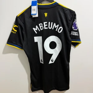 Manchester United 25/26 3rd #Mbeumo 19 Player Edition - Premier League - Till salu: Manchester United-tröja med Mbeumo namn och nummer 19 Tredjetröja med vita detaljer (säsong 2025/26)  Märke: Adidas Storlek: S Skick: Nytt med tagg  Officiell PREMIER LEAGUE -patch på ärmen  Lätt och andningsbart material – perfekt både till match och vardagsbruk. Ett utmärkt val för både Manchester United- och Mbeumo-fans! Detta är den officiella matchtröjan.  #manutd #mbeumo #premierleague #manchesterunited #jerseypremierleague #jersey #ucl #championsleague