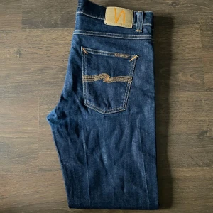 Mörkblå jeans från Nudie Jeans - Säljer ett par riktigt fräscha och stilrena jeans från nudie i utmärkt skick, inga defekter eller liknande utan felfria. Passar perfekt till allt och en otroligt snygg mörk färg som enligt mig är extra snygg, skriv privat vid minsta fundering🙌🏻👌🏻
