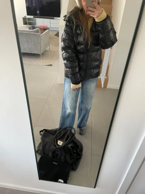 Svart glansig pufferjacka med huva från rock and blue  - Säljer nu en svart glansig pufferjacka från Rock And Blue med huva och dragkedja. Då jackan inte kommer till användning hemma hos mig. Jackan är vadderad och har en oversized passform, perfekt för kalla dagar. Enkel och stilren design som funkar till det mesta 🥰