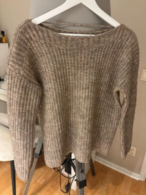 Beige stickad tröja Vero Moda S - Mysig beige stickad tröja från Vero Moda i storlek S. Tröjan har en grovstickad struktur, rund halsringning och långa ärmar. Perfekt för lager på lager under kyliga dagar.