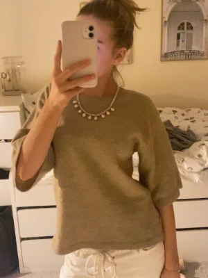 Beige stickad tröja med trekvartsärm - Mysig beige stickad tröja med rund halsringning och trekvartsärmar. Tröjan har en enkel och stilren design som är lätt att matcha med olika outfits. Perfekt under kyligare dagar.