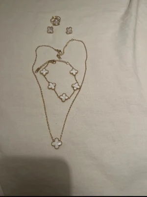 Fyrklöver set - Bilderna på bilden visar fyrklöver set av guldpläterade 18k med vita stenar. Set av halsband, armband, örhängen och ring. 