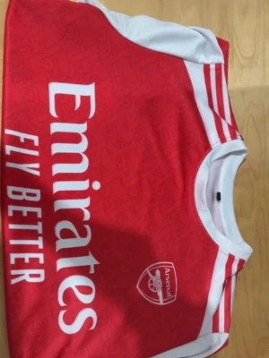 Arsenal tröja Rice 41 - Säljer en officiell Arsenal tröja med Rice 41 på ryggen. Tröjan är röd med vita detaljer och har klubbmärket samt Emirates sponsortryck på bröstet. Perfekt för alla Arsenal fans!