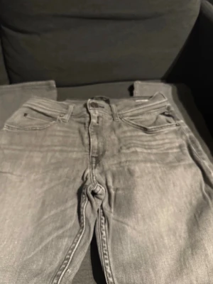 Grå jeans från Replay, modell Wallys - Säljer ett par grå jeans från Replay, modell Wallys. Klassisk femficksdesign, raka ben och snygga detaljer på bakfickorna. Jeansen har normal passform och är tillverkade i mjukt bomullsmaterial med en tvättad look. Perfekta till en avslappnad stil.