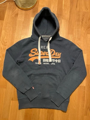 Superdry hoodie  - Snygg Superdry hoodie i storlek S. Blågrå färg och i väldigt fint skick! Hör av dig gällande frågor
