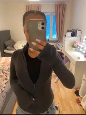 Svart zip hoodie med lång ärm - Säljer en grå träning flis dragkedja och lång ärm. Tröjan har en slim passform och är perfekt för lager-på-lager. Enkel och stilren design som funkar till många outfits.