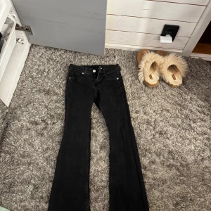 Svarta bootcut jeans - Säljer ett par svarta jeans med bootcut-modell. Byxorna har klassisk femficksdesign, knapp och dragkedja framtill. Materialet är jeans och färgen är helt svart, vilket gör dem enkla att matcha med olika stilar.