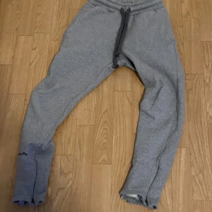 Grå mjukisbyxor från syna world - Grå mjukisbyxor från syna world med elastisk midja och svart snörning. Byxorna har en relaxed passform och är fodrade med mjukt material på insidan för extra komfort. Perfekta för chill dagar eller när du vill vara bekväm.