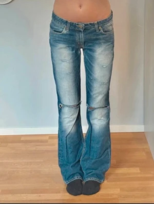 Blå bootcut jeans från Lee, stl 27/33 - Säljer ett par blå bootcut jeans från Lee. Jeansen har slitningar vid knäna, . Snygg tvätt med ljusare partier och Lee-logga bak i midjan.
