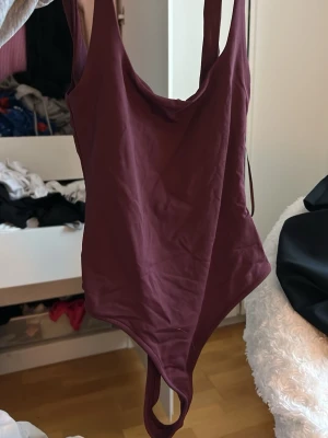 Vinröd body med djup rygg - Säljer en enkel och stilren vinröd body med breda axelband och djup urringning både fram och bak. Materialet är mjukt och stretchigt. Oanvänd 