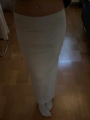 Ljusbeige långkjol  - långkjol i ljusbeige färg. Kjolen har en tight passform och är gjord i ett mjukt, stretchigt material.