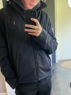 Polo Ralph Lauren Windbreaker - Svart vindjacka från Polo Ralph Lauren i gott skick, finns vissa tecken på andvändning. Stilren design som funkar till många olika outfits. Skriv vid frågor eller funderingar