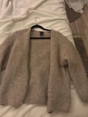 Mörk beige stickad kofta från Lindex - Mysig beige/ljusbrun stickad kofta från Lindex i storlek M/L. Koftan har en öppen front, lång ärm och en loose passform💗💗 Perfekt för lager på lager under höst och vinter. Materialet är mjukt och fluffigt, vilket ger en avslappnad vibe. Se sista bilden för lagad defekt 