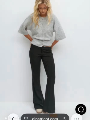 Svarta bootcut kostymbyxor Gina Tricot - Snygga svarta kostymbyxor från Gina Tricot med bootcut-snitt och normal passform. Byxorna har låg midja midja, bälteshällor och klassisk design. Perfekta till en chill eller dressad look. Materialet är troligtvis polyesterblandning för en skön känsla. Aldrig använda 