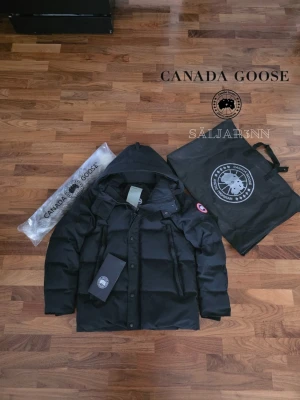 Canada Goose WyndHam Parka Red Label | Strl M - Exklusiv Canada Goose Wyndham Parka Red Label i klassisk svart. En mycket eftertraktad modell med den ikoniska röda loggan, känd för sin höga kvalitet, stilrena passform och extrema värme. Perfekt anpassad för nordiskt vinterklimat med kraftig dunfyllning, slitstarkt yttertyg och skyddande huva. Påsen på bilden medföljer ej. Jackan är i nyskick. 📦 Snabb leverans – skickas samma dag (om ej hindr.) 📩 Hör av dig vid frågor eller intresse