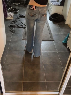Lågmidjade bootcut jeans - Säljer dessa sjukt snygga ljusblå bootcut jeansen. Jeansen har låg midja, dekorativa knappar på fickorna och slitningar framtill. Perfekt för dig som gillar retrovibe. Skulle säga att de passar någon som är runt 160 cm. Priset kan diskuteras💓 OBS. bilderna är lånade från förra ägaren då dem inte passade mig men det är bara att fråga om fler bilder!!