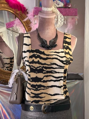 Zebra/Tiger animal print mönstrat linne - Snygg figurnära animal print topp med zebramönster och lite glittriga detaljer i tyget. • Brand: Pas De Quoi • Storlek: M/L (väldigt stretchig) • Skick: Super fin skick, men har några mindre fläckar nedtill (se sista bilden). Inget som stör helhetsintrycket vid användning. 
