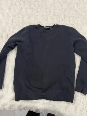 Svart sweatshirt från Sail Racing L - En svart sweatshirt från Sail Racing i storlek L. Tröjan har rund halsringning, diskret logga framtill och långa ärmar. Tillverkad i mjuk bomull som känns skön mot huden. Perfekt för dig som gillar enkel och stilren design.