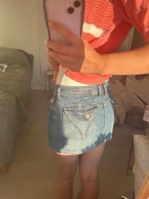 Blå lågmidjad jeanskjol  - Blå lågmidjad jeanskjol från Wild Girl Jeans. Kjolen är kort och har snygga fickor bak med detaljer och knappar. Kjolen är 30cm lång!  Den är storlek 27 (38cm rakt över) !! Supersnygg nu i sommar!💗