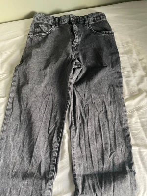 Grå jeans från Woodbird 32 i längd och 27 i midjan  - Säljer ett par grå jeans från Woodbird med klassisk femficksdesign och raka ben. Jeansen har bälteshällor, knapp och dragkedja framtill. Materialet är slitstarkt denim i bomull och färgen är tvättad grå för en cool vintagekänsla.