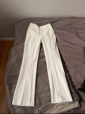 Vita kostymbyxor med bootcut - Snygga vita kostymbyxor från Bik Bok. Byxorna är bootcut och i modellen Vilma.  Helt nya med prislappen kvar. Nypris 500 kr. Storlek 34/36 