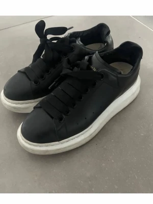 Svarta sneakers från Alexander McQueen - Säljer mina Alexander mcqueen köpta på NK 2019. De har defekter i innersidan av skon (syns på sista bilden) syns ej när man har på sig dom. Annars i bra skick. Storlek 36 men är stora i strl så de är en 37a
