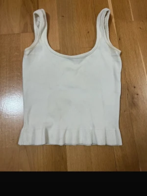 Vit ribbad linnetopp från Bik Bok - Säljer en enkel och stilren vit linnetopp från Bik Bok i storlek XS. Toppen är ribbad nertill och har breda axelband samt rundad halsringning. Perfekt att matcha med jeans eller kjol för en clean look.