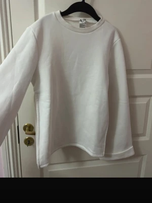 Lång tjocktröja med slits vid sidorna  - En vit lång tjocktröja med långa ärmar och slit vid sidorna. Oversize i storleken.