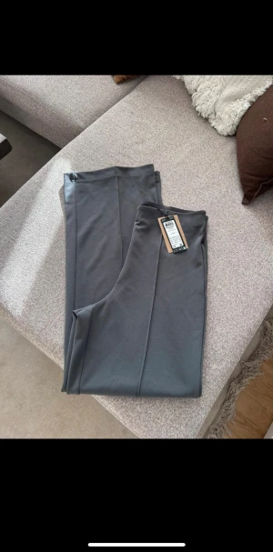 Nya kostymbyxor med rak passform - Snygga grå kostymbyxor med rak passform och minimalistisk design. Byxorna har hög midja och är tillverkade i ett mjukt, stretchigt material.