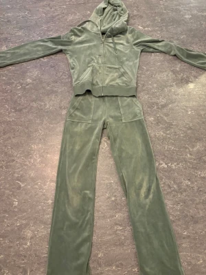 Gröna juice byxor  - Säljer snygga gröna juicy byxor i mjuk velour. Byxorna har fickor fram och bak med knappdetaljer bak. Perfekta för chill och avslappnad stil, matcha med hoodie för en komplett look. Byxorna är i storlek Xss och hoodien i S. Dock är de lite slitna vid knäna och det fins små fläckar, därför kan pris diskuteras.