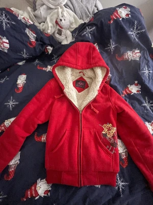 Cool zip up - Snygg röd zip up från Trandy med coolt 2000s tals print på varm och bra för vintern och hösten det står storlek M men passar även S passar på både tjejer och killar!!