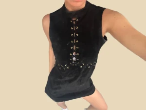 Äkta mockaklänning med snörning brun - Cool vintage klänning i äkta mocka med högt halslinje och snörning framtill med guldfärgade öljetter. Klänningen är ärmlös och har snörningsdetaljer även i midjan för extra edge. Nypris ca 4000kr!!🤎🤎🤎🤎