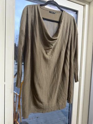 Beige stickad tröja från Vila - Säljer en beige stickad tröja från Vila i storlek XS. Tröjan har en snygg draperad halsringning och trekvartsärmar med ribbade detaljer. Perfekt för dig som gillar en chill och stilren look.