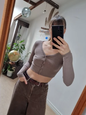 Cropped long sleeve - Cropped long sleeve in ribbed fabric, 96% cotton. The color is camel/light brown and leans toward a dusty pink undertone (which you see in picture 2+3) Length: 34 cm.